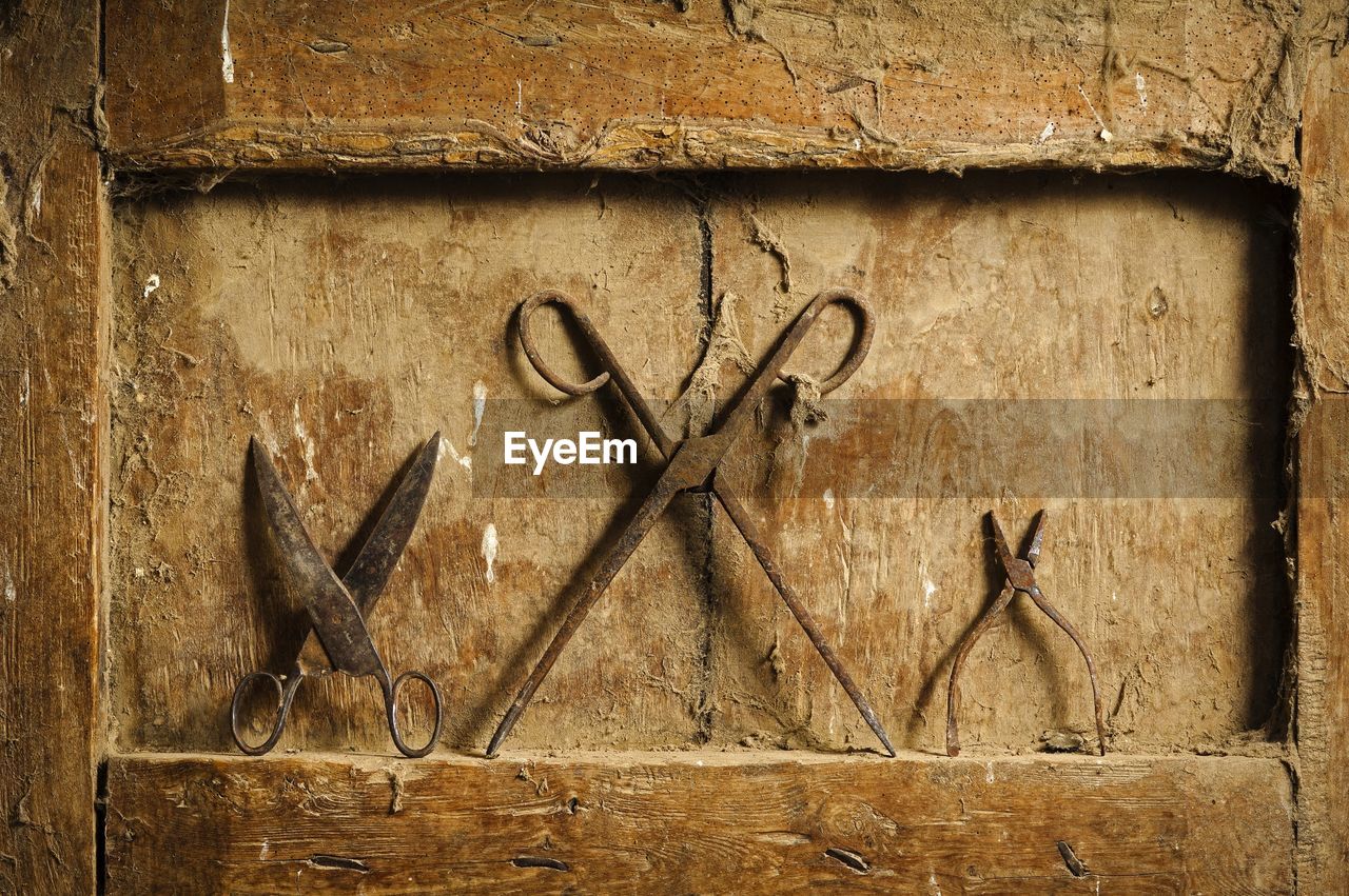 Close-up of rusty scissors and pliers on dirty wooden niche