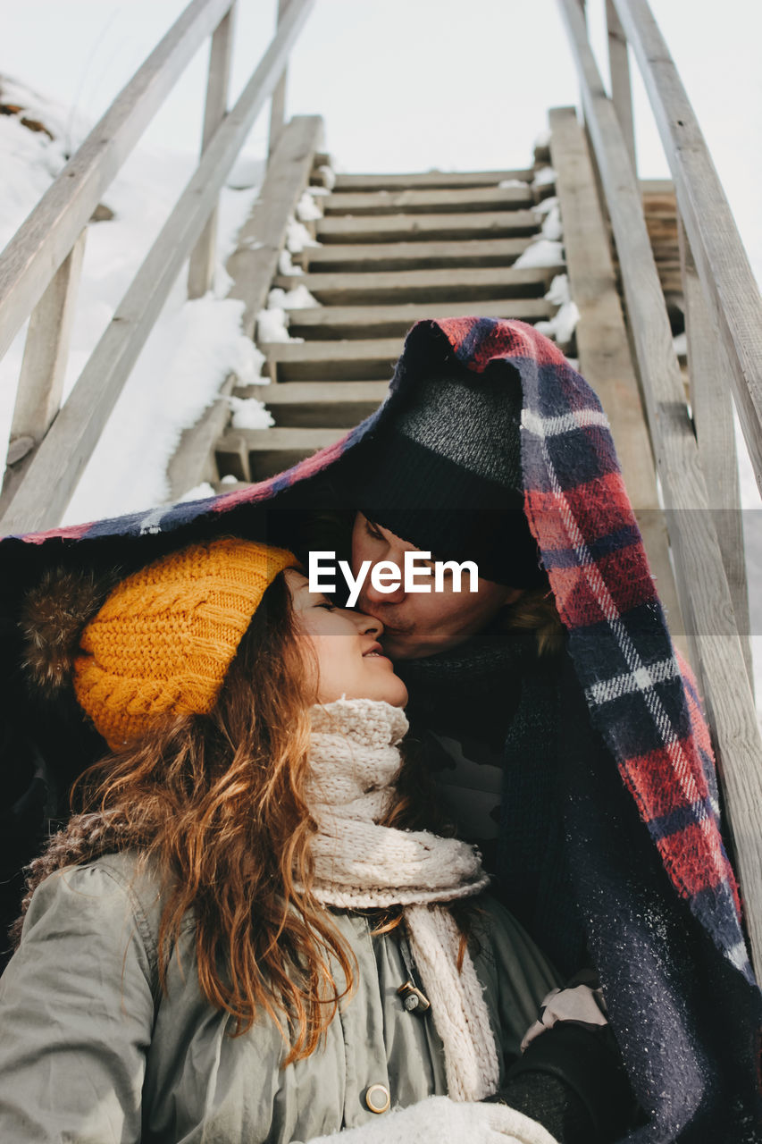 Couple in warm clothing kissing on steps