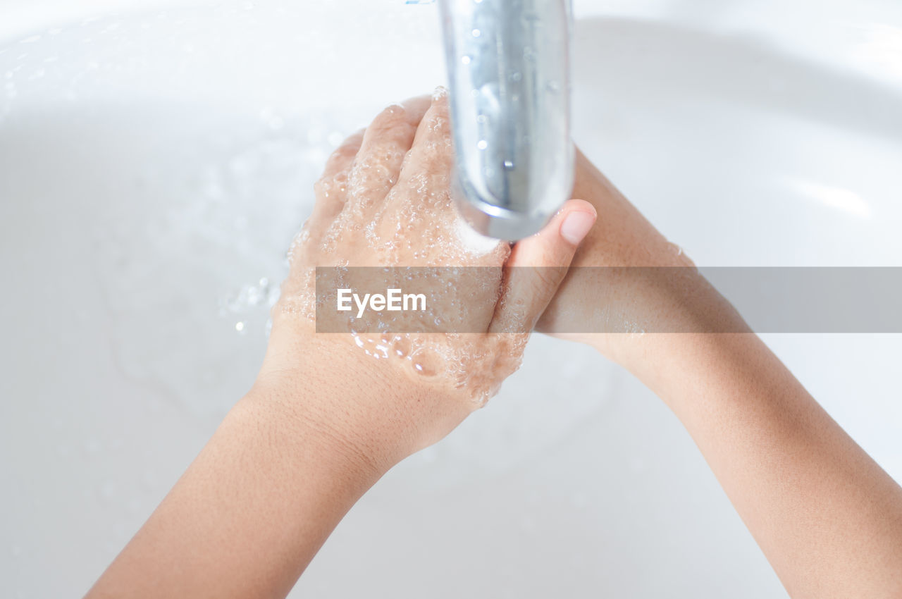 Close-up of person washing hands under faucet