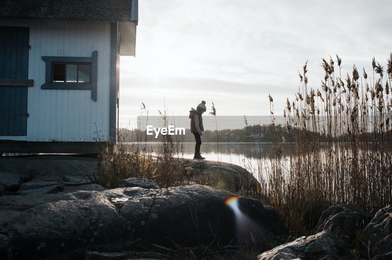 Young girl stood on the rocks next to a traditional swedish hut