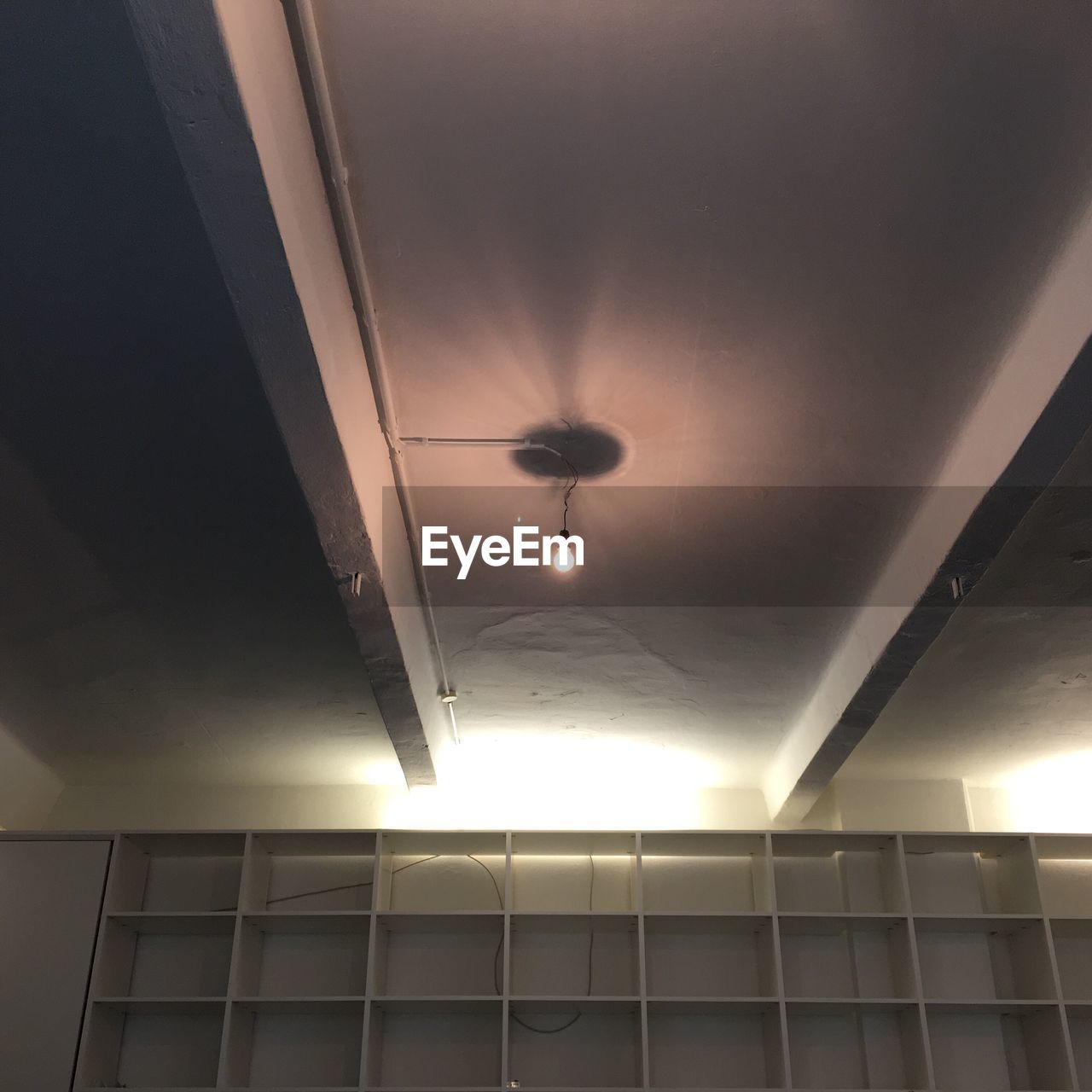 Low angle view of illuminated light bulb hanging in empty office