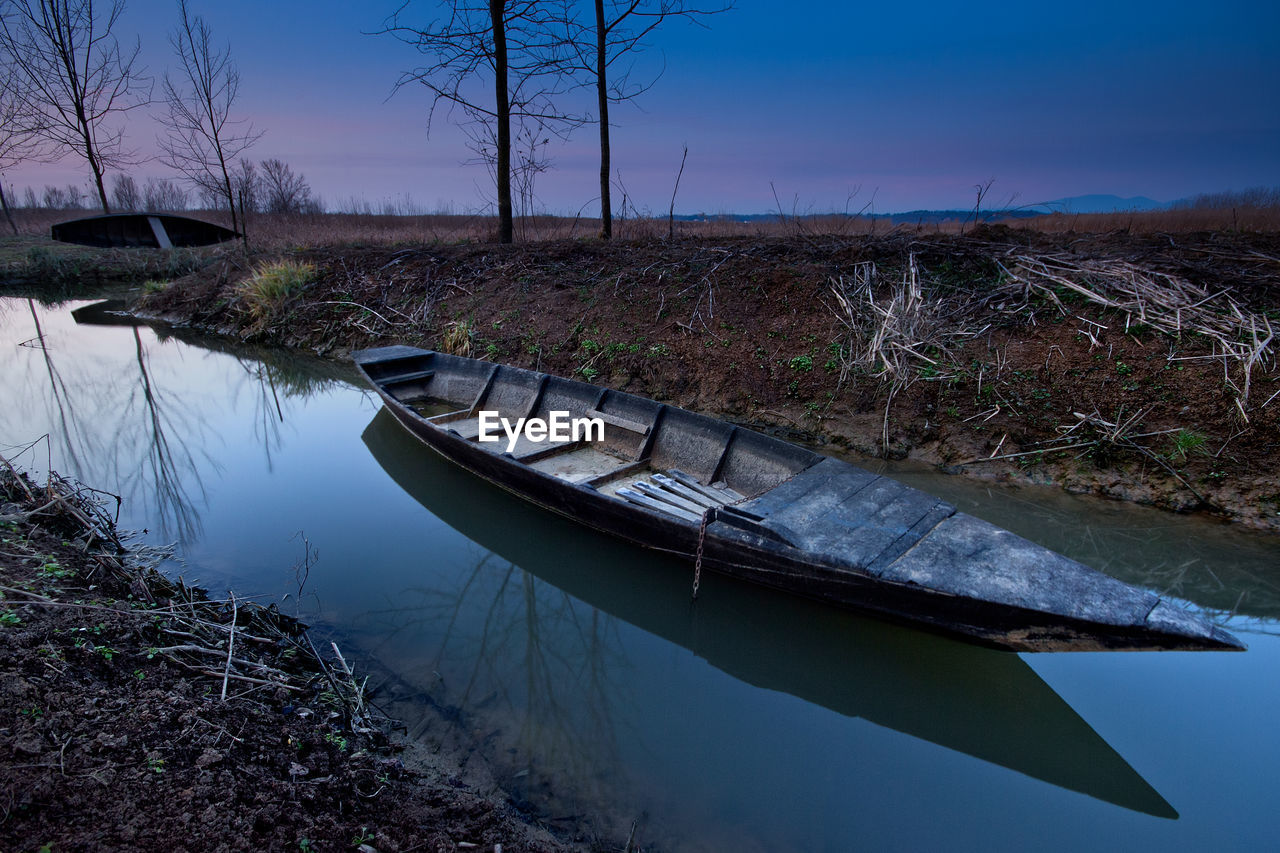 BOAT MOORED ON SHORE AGAINST SKY