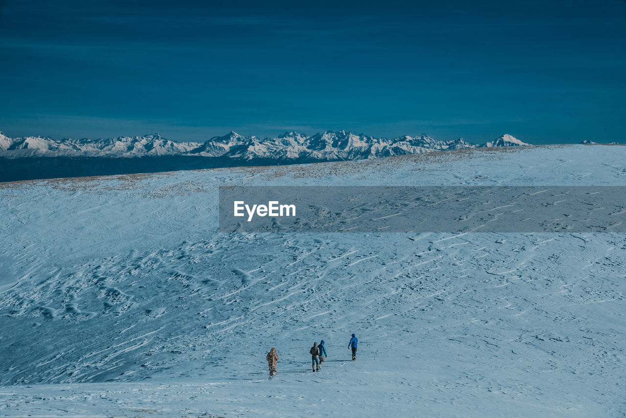 High angle view of people walking on snow covered land against sky