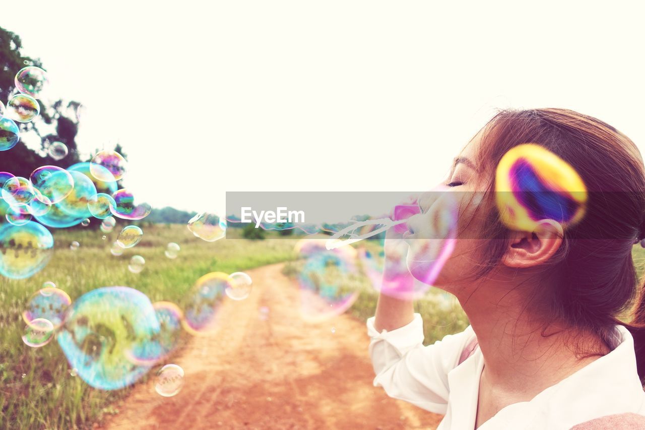 PORTRAIT OF WOMAN WITH BUBBLES IN PARK