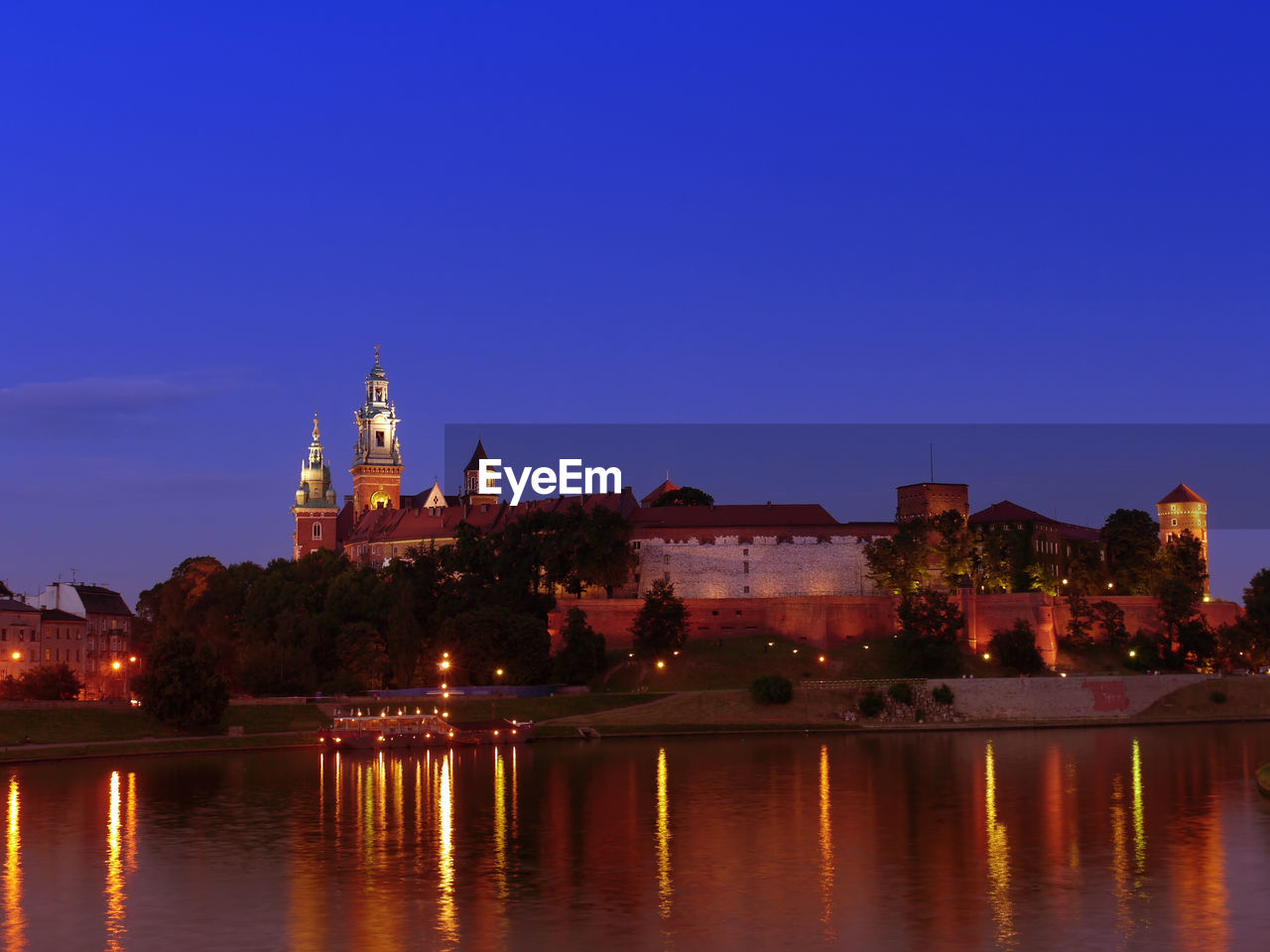 Royal wawel castle illuminated at night reflecting in the vistula river, krakow - poland