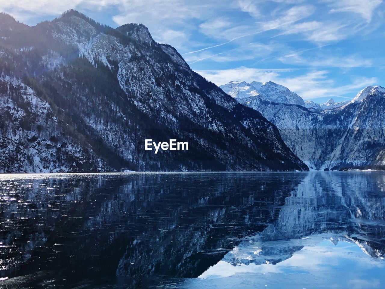 Scenic view of lake by snowcapped mountains against sky