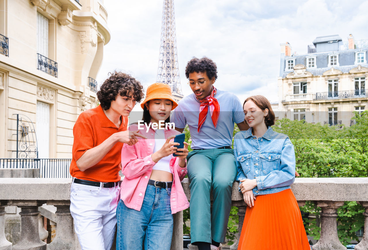 portrait of smiling friends standing against buildings in city