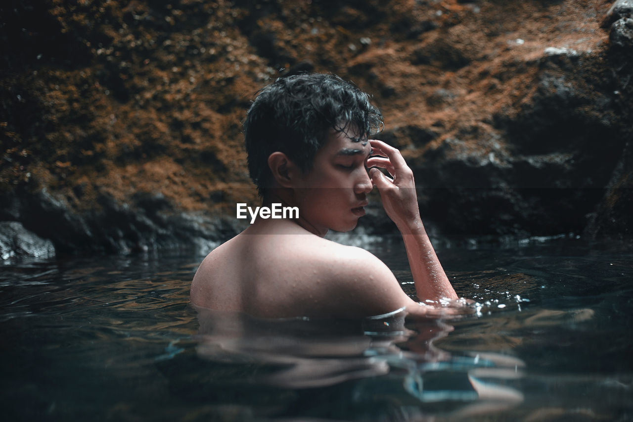 Portrait of shirtless man in swimming lake