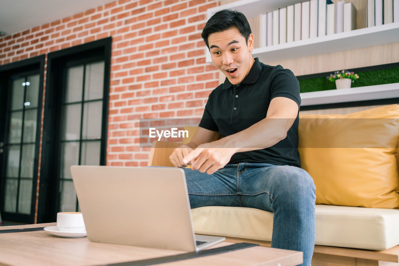 Happy businessman pointing at laptop in office