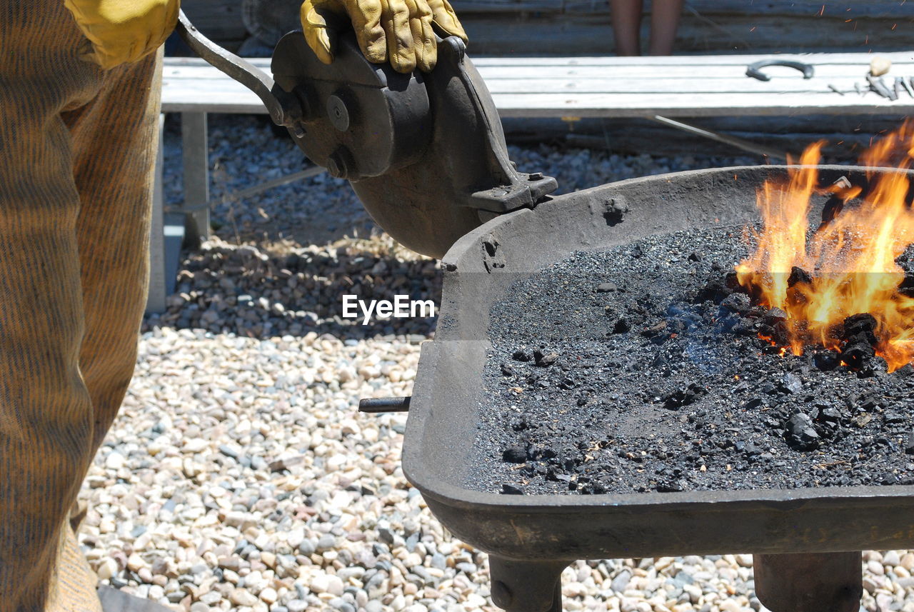 Male farrier burning a horse shoe outdoors in the coals.