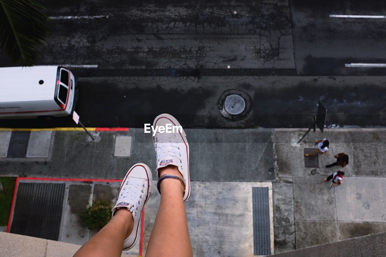 Low section of woman sitting on building terrace over road