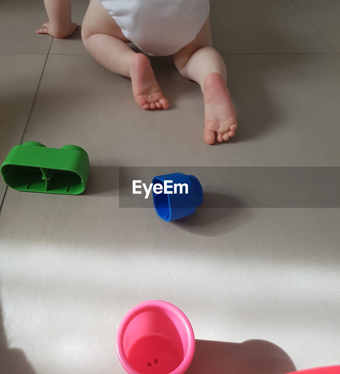 LOW SECTION OF BOY PLAYING WITH TATTOO ON THE FLOOR