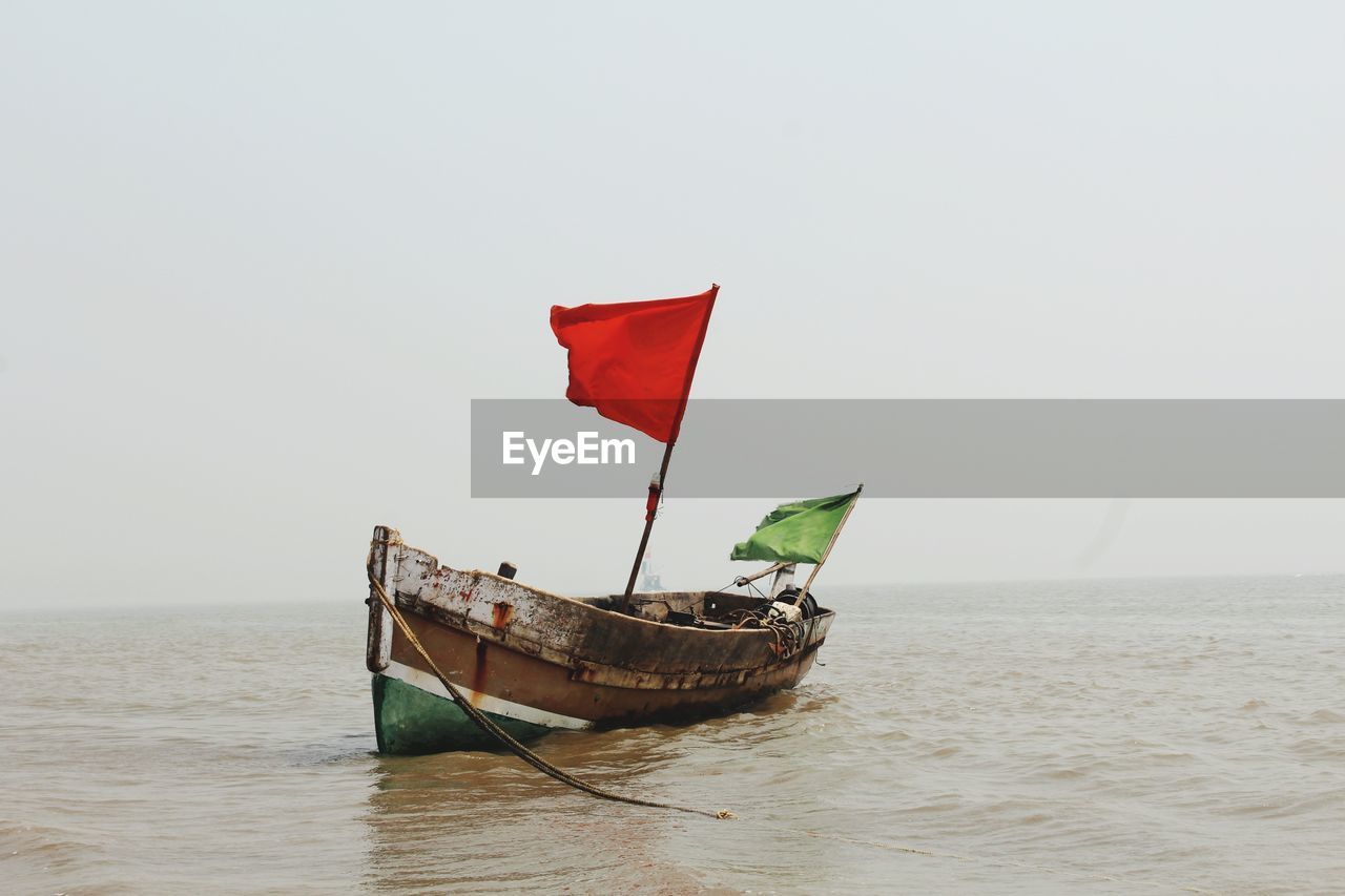 Flag on boat in sea against clear sky