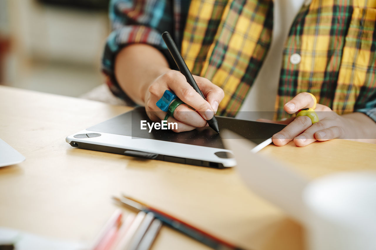 Young illustrator using graphic tablet at desk in office