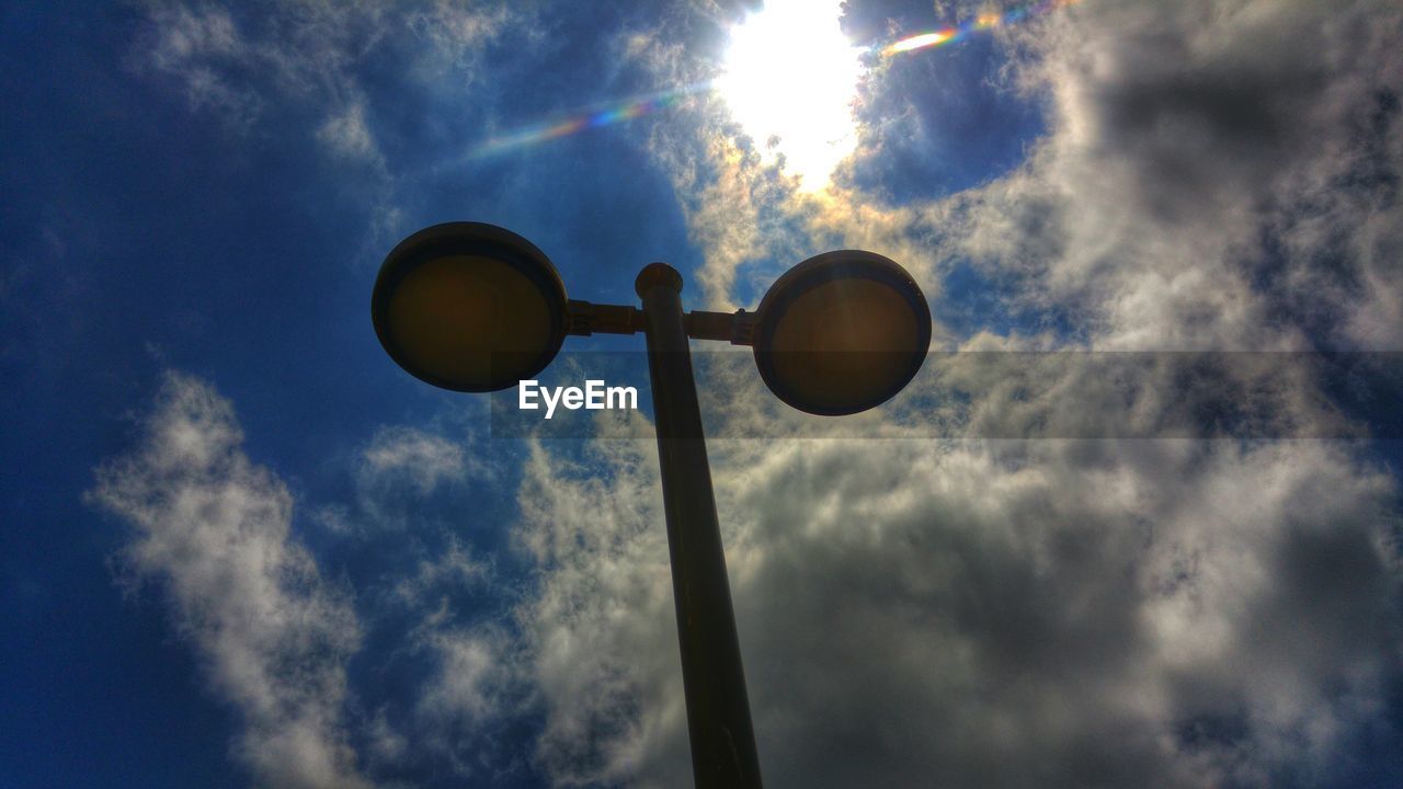Low angle view of street light against cloudy sky on sunny day