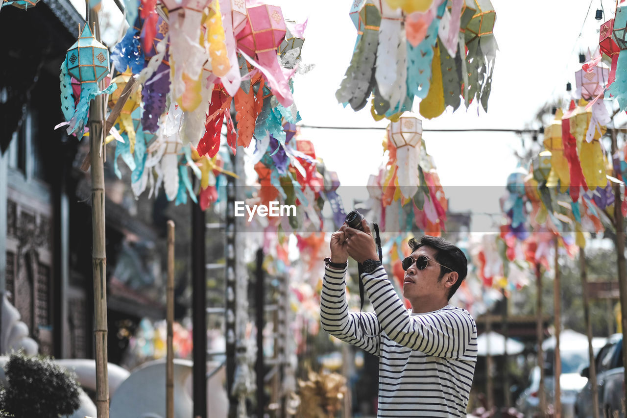 Man photographing colorful lanterns in city