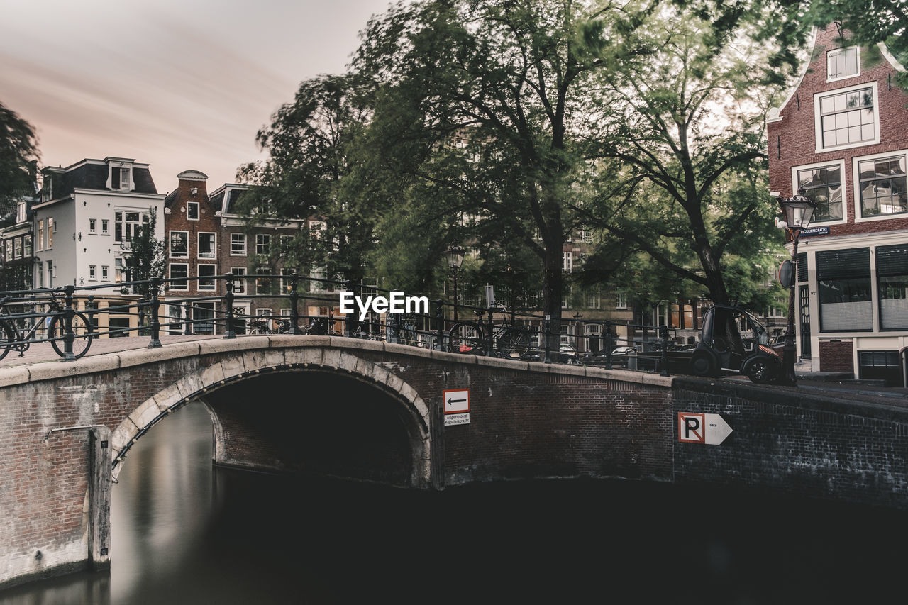 Arch bridge over canal amidst buildings in city