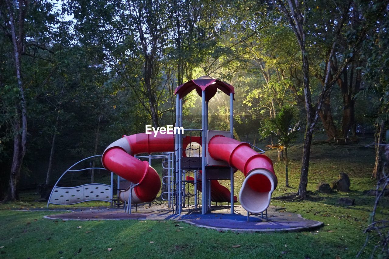 Empty playground against trees in park