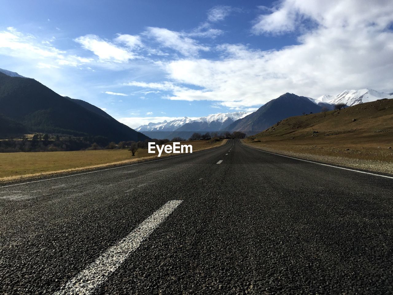 View of empty road by field against sky