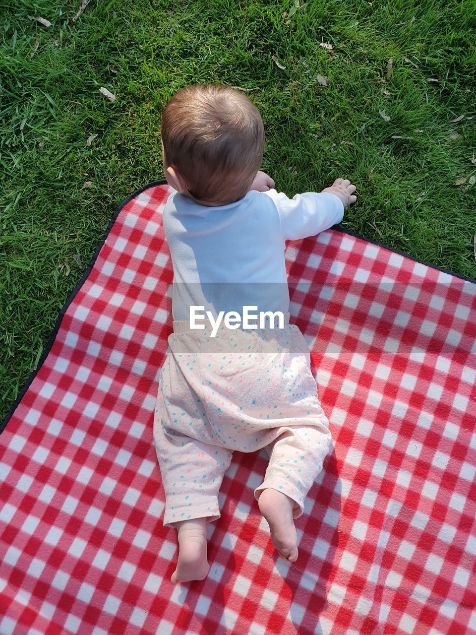 High angle view of cute baby girl lying on picnic blanket 