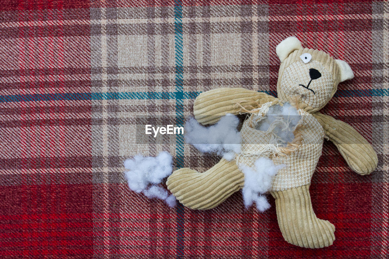 High angle view of torn teddy bear on bed