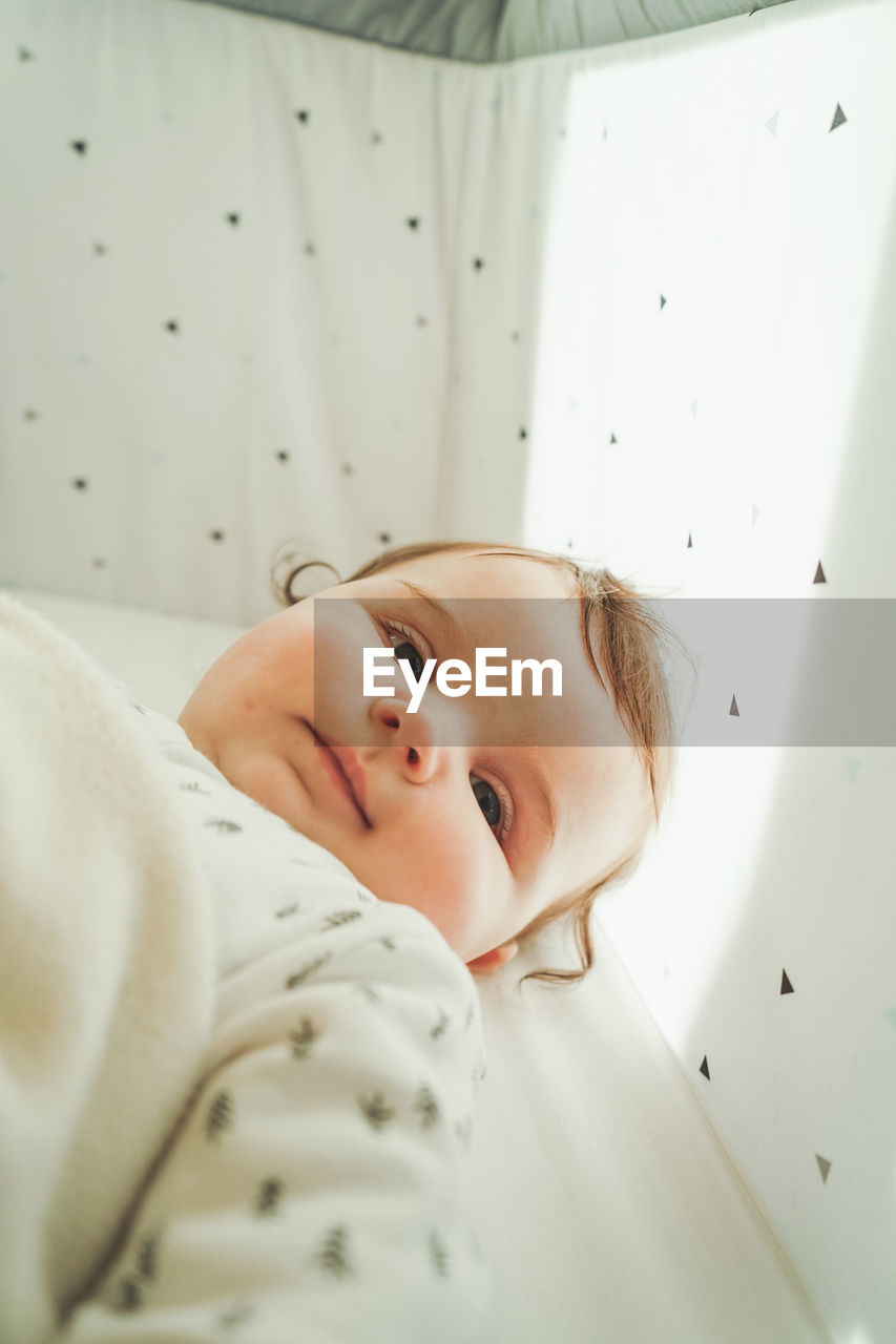 Directly above shot of cute baby girl lying on bed at home