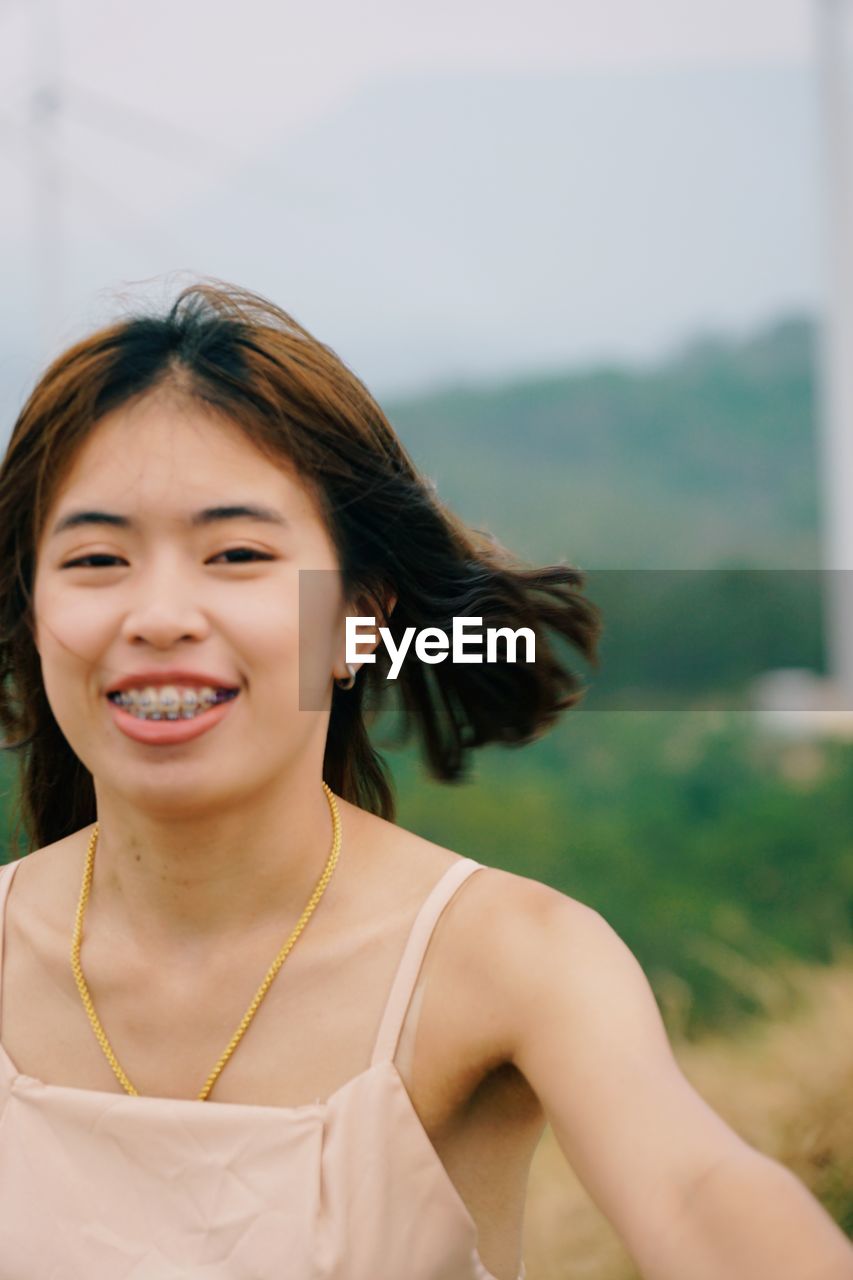 PORTRAIT OF SMILING YOUNG WOMAN