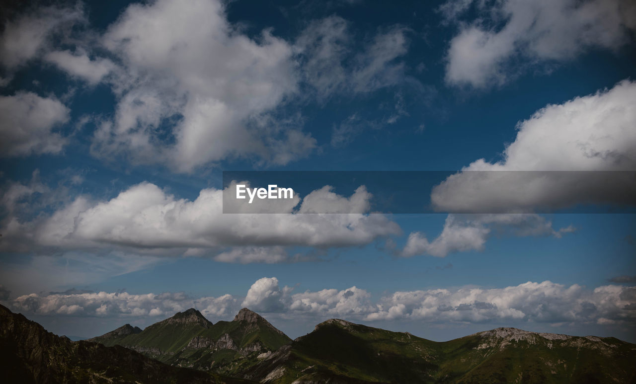 Low angle view of mountain range against cloudy sky