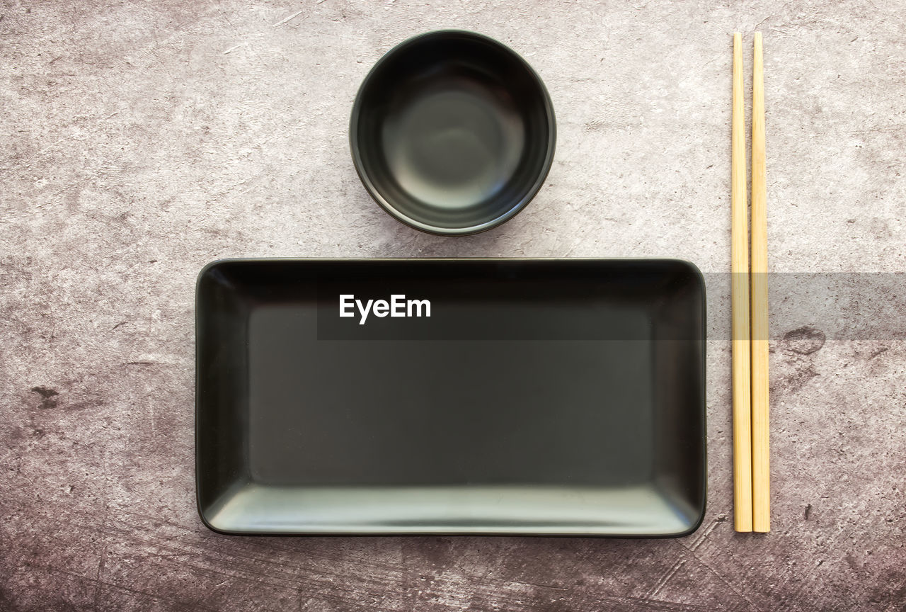 Black slate plate with chopstick grey concrete background. flat lay. asian food concept