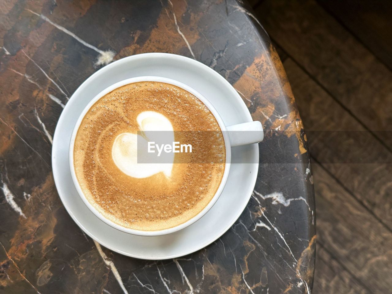 Top view of cup of cappuccino coffee with latte art on marble table background.