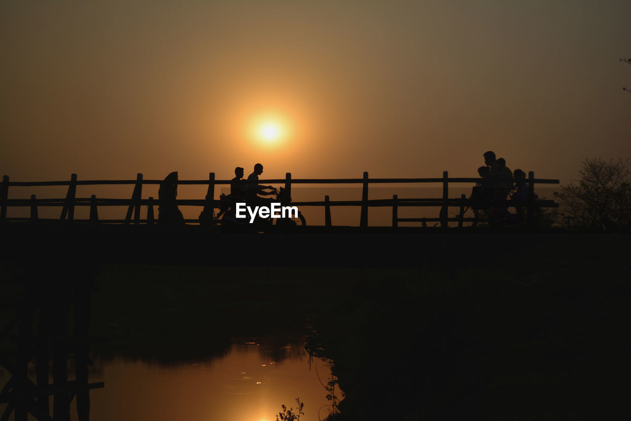 SILHOUETTE PEOPLE RIDING BICYCLE ON LAKE DURING SUNSET