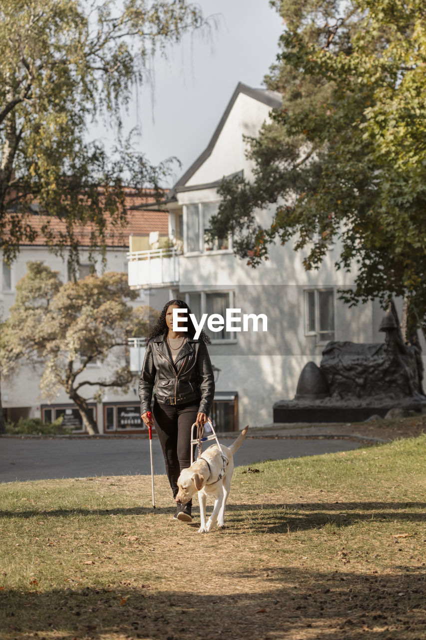 Visually impaired woman walking on lawn with guide dog