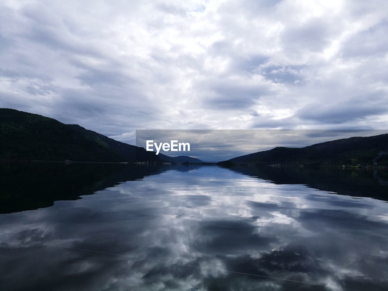 Scenic view of lake by mountains against sky