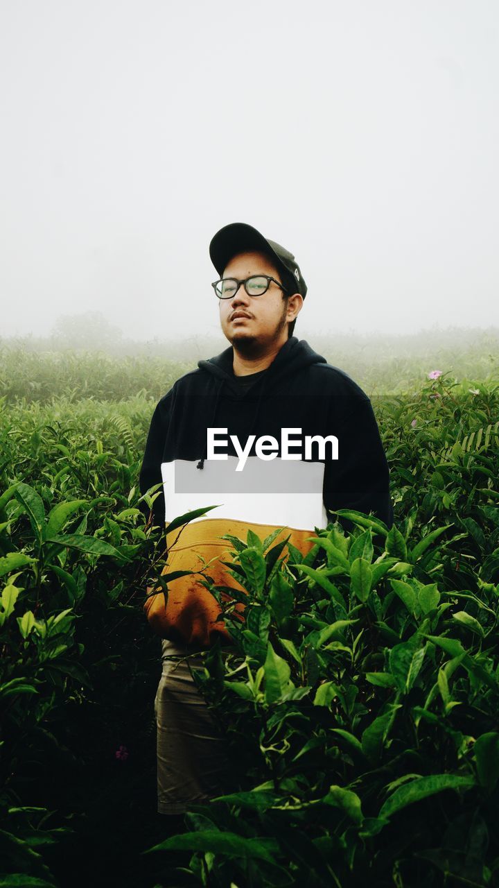 YOUNG MAN LOOKING AWAY WHILE STANDING ON LAND