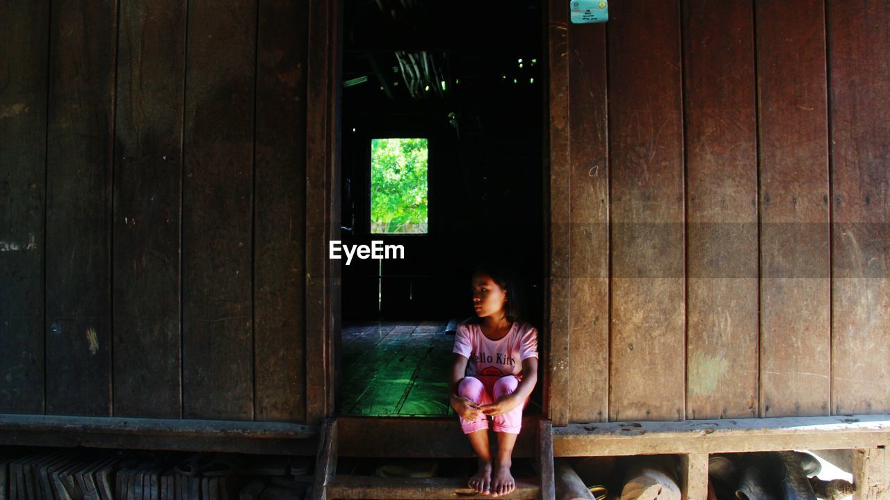 GIRL SITTING ON WOODEN FLOOR