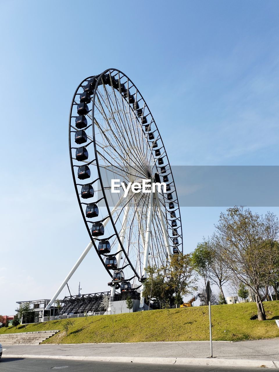 ferris wheel, amusement park ride, amusement park, sky, arts culture and entertainment, architecture, nature, transportation, city, wheel, travel destinations, park, built structure, day, travel, no people, recreation, outdoors, geometric shape, tourism, tree, circle, shape, plant, landmark, blue, road