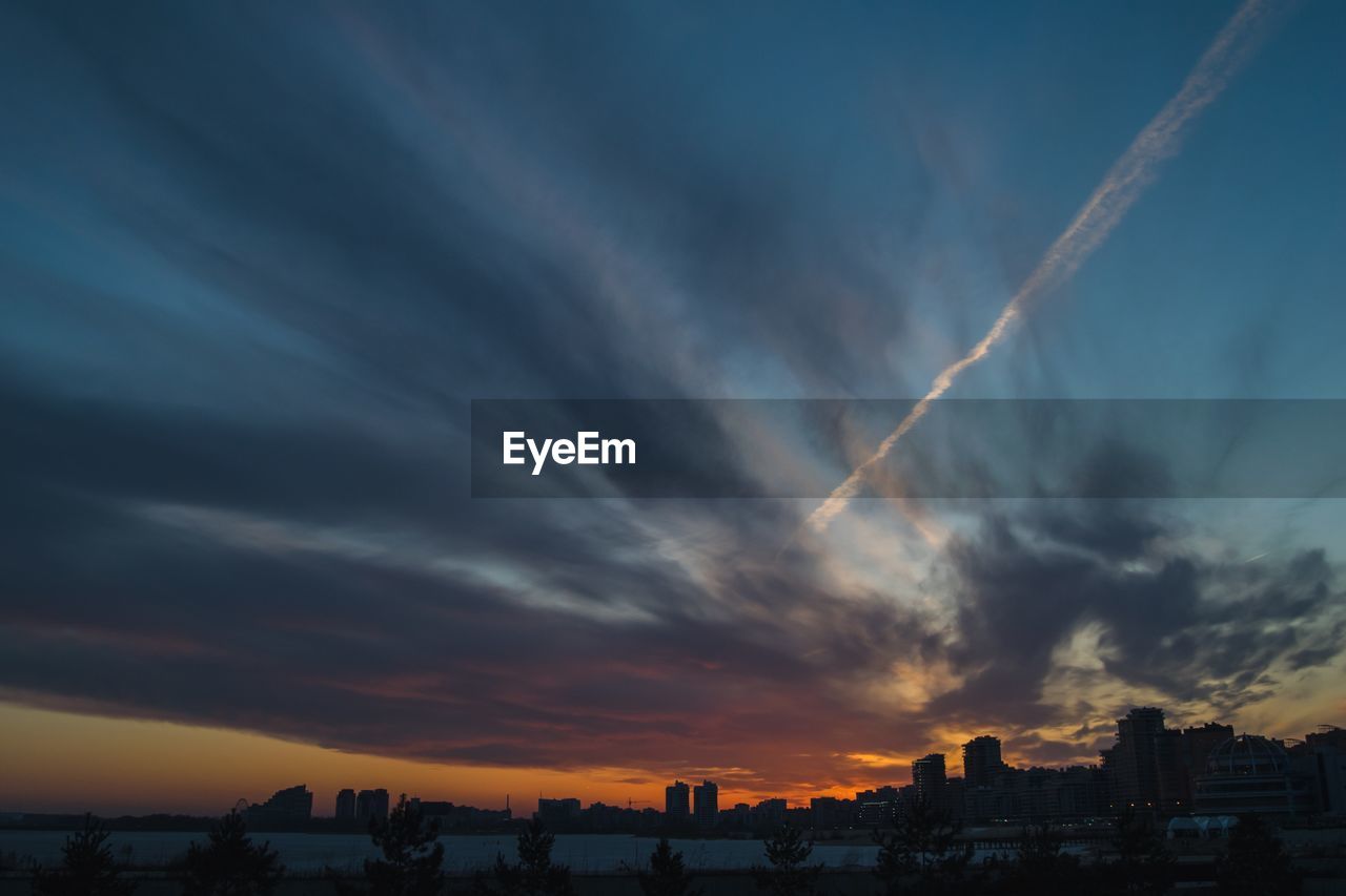 Scenic view of dramatic sky over city during sunset