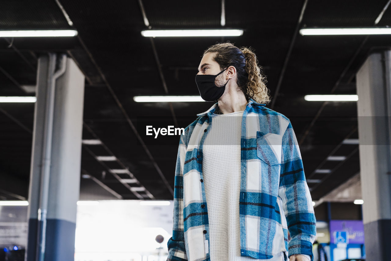 Man wearing face mask looking away while standing at underpass