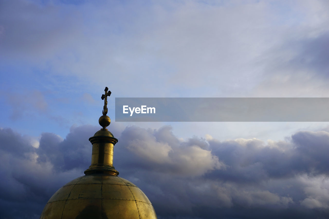 Low angle view of cross against building against sky