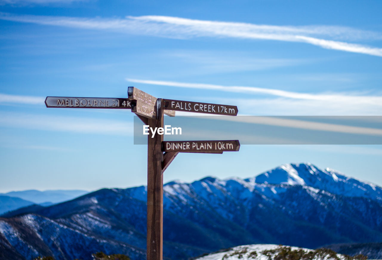 Information sign on snowcapped mountains against sky