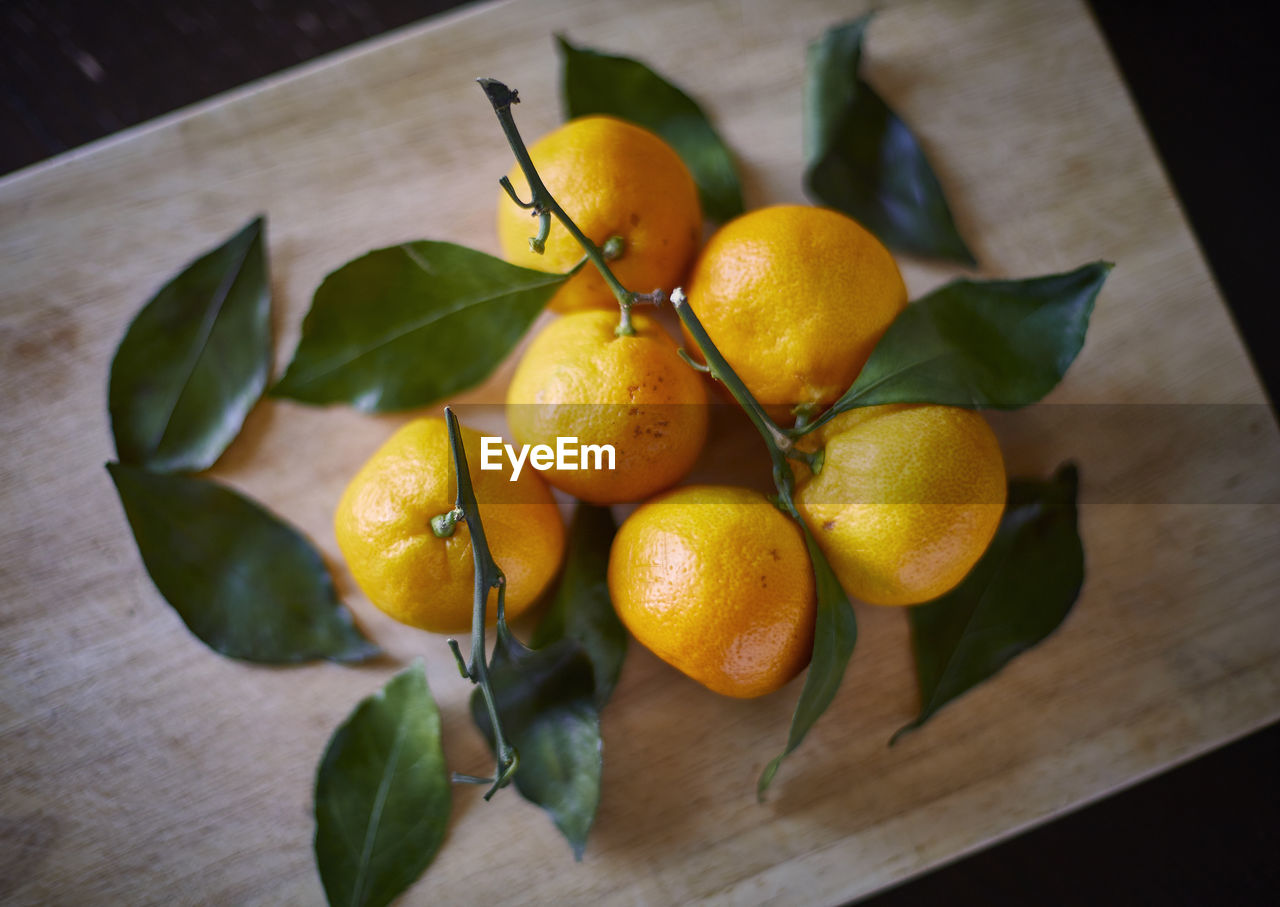 food and drink, food, healthy eating, freshness, fruit, citrus, plant, produce, leaf, wellbeing, plant part, citrus fruit, yellow, lemon, wood, no people, clementine, nature, table, tangerine, indoors, orange, high angle view, close-up, still life, orange color, flower, calamondin, group of objects