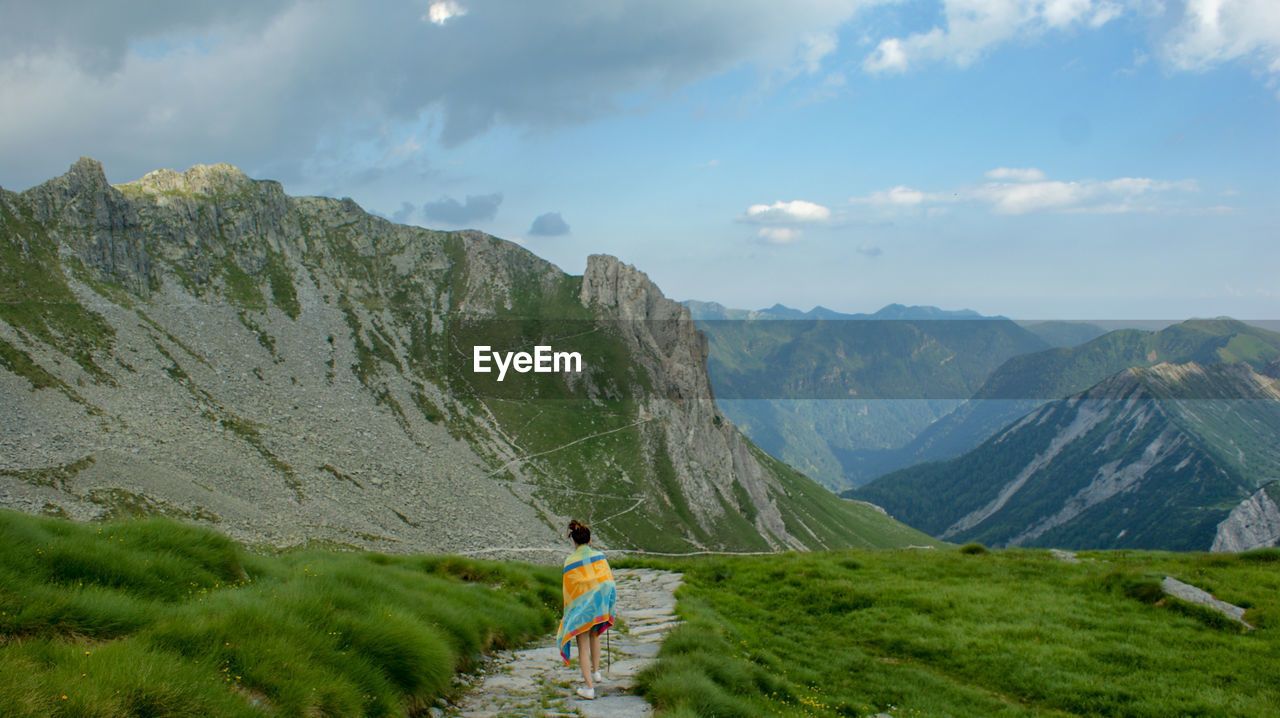 Rear view of woman standing on land against mountains