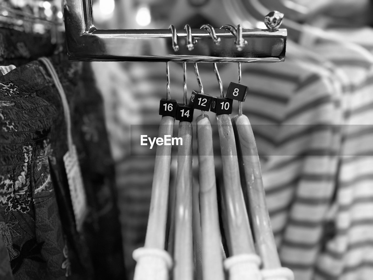 black, black and white, hanging, monochrome photography, white, monochrome, focus on foreground, no people, retail, close-up, coathanger, day, store, selective focus