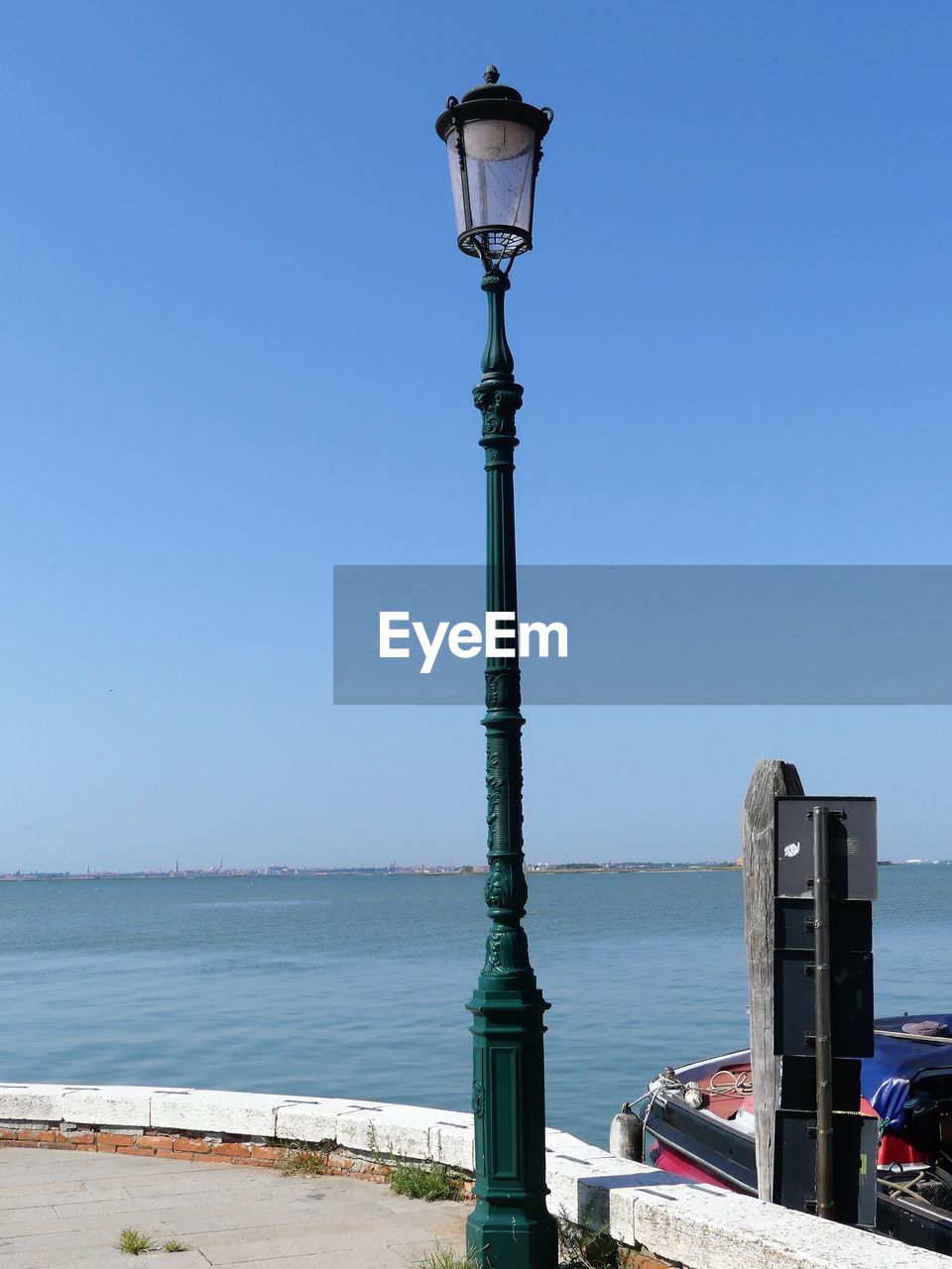 Street light by sea against clear blue sky