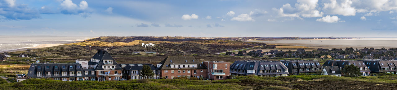 Panoramic view of buildings against cloudy sky