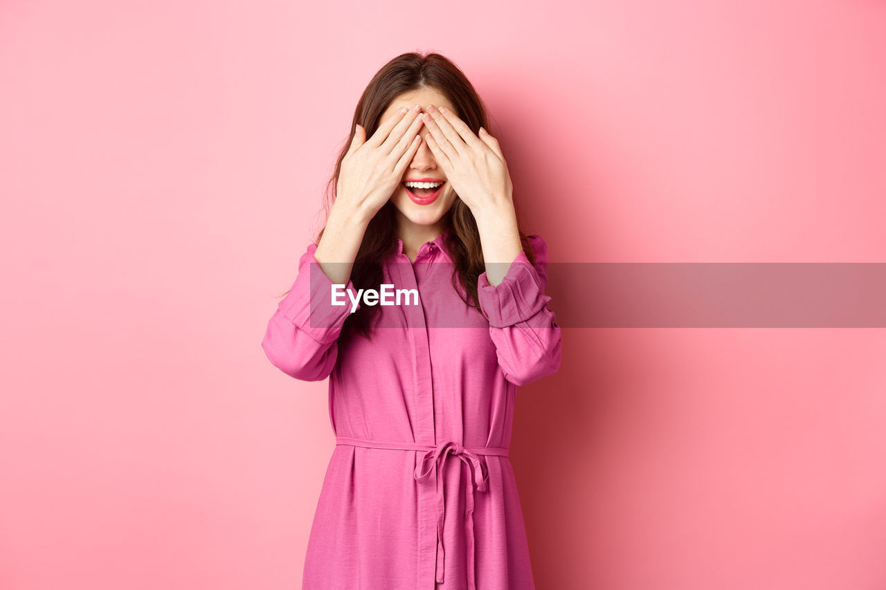 Woman standing against pink background