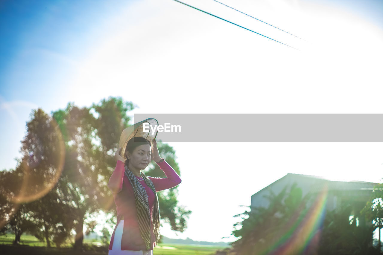 lens flare, sky, sunlight, nature, one person, day, happiness, women, low angle view, copy space, childhood, child, adult, back lit, tree, summer, sunbeam, fun, lifestyles, smiling, enjoyment, outdoors, clothing, plant, leisure activity, sunny, sports, emotion, carefree, female, person, standing, vitality, cheerful, holding, sun, hat
