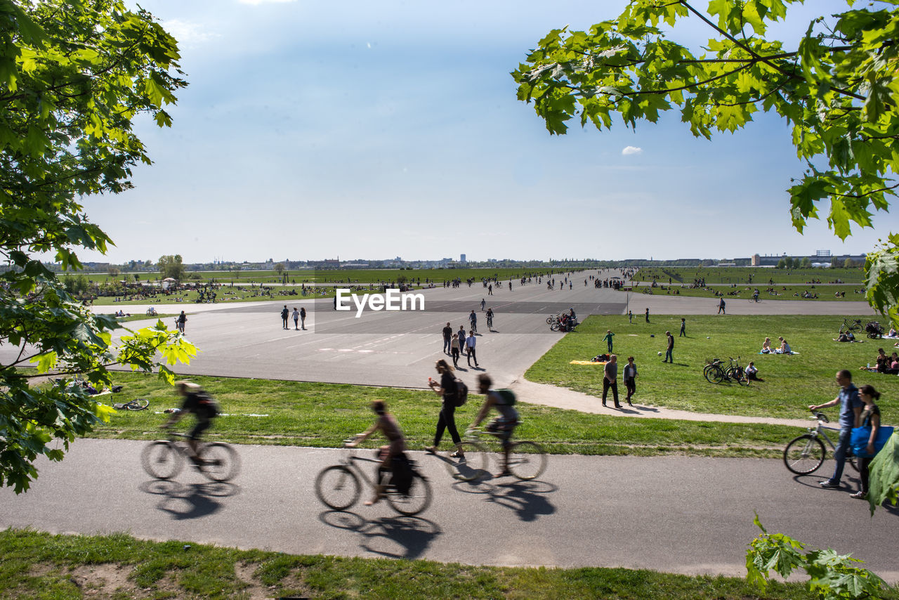 People riding bicycle on road against sky