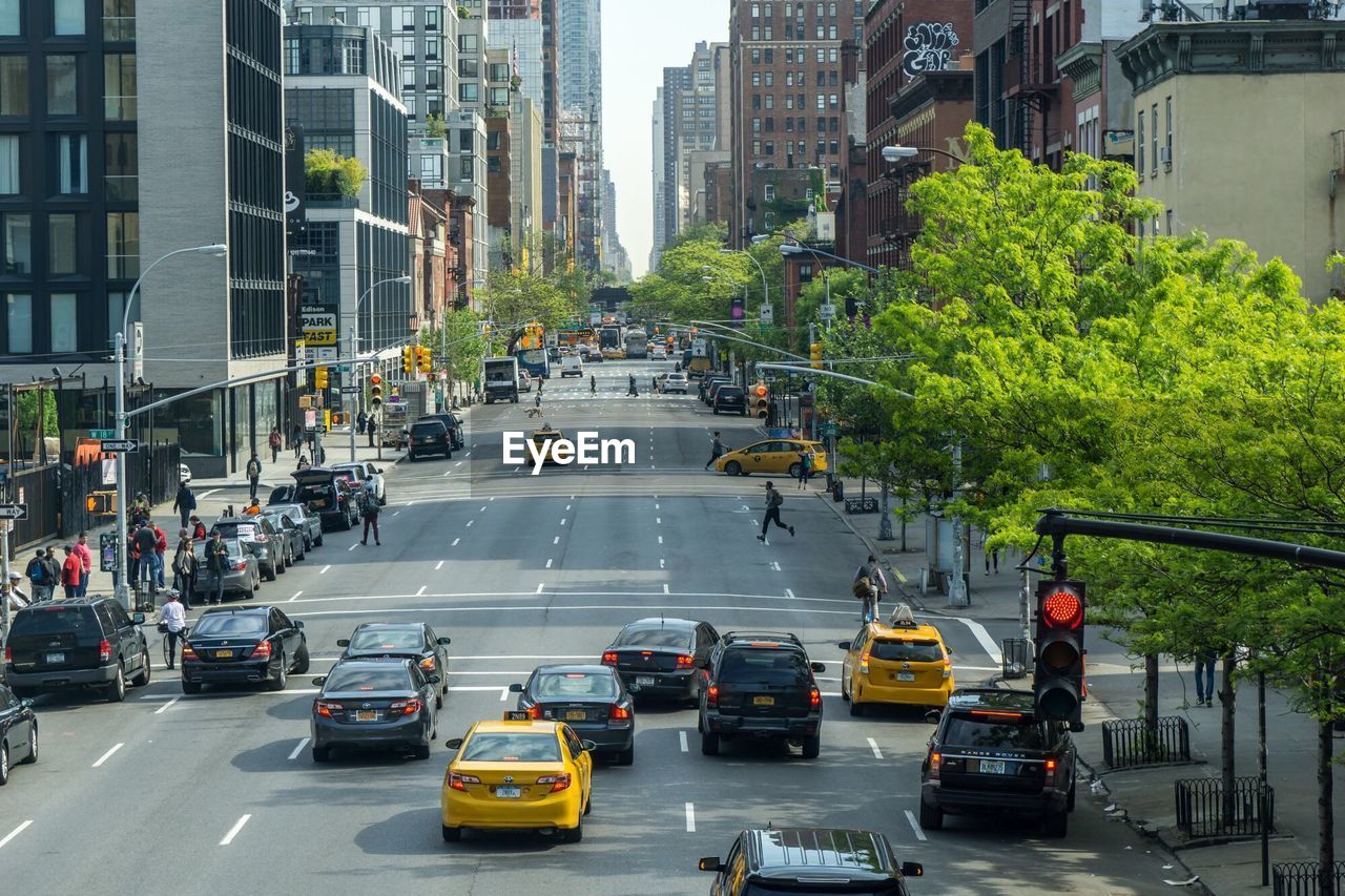 Cars and people on road amidst buildings in city