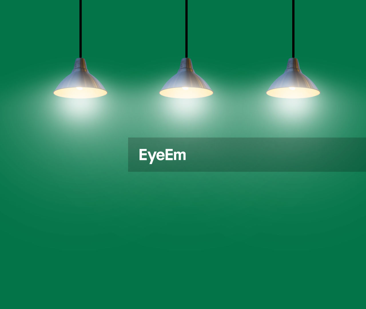 Illuminated light bulbs hanging against green background